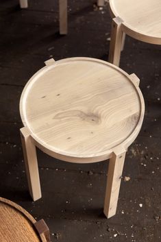 two wooden stools sitting next to each other on top of a black floor covered in dirt