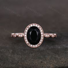 an oval shaped black diamond ring with diamonds around the band on a stone surface in front of