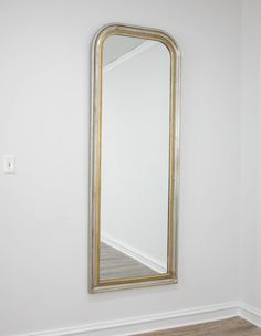 an empty room with a mirror on the wall and wood flooring in front of it