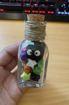 a hand holding a glass bottle filled with colorful items