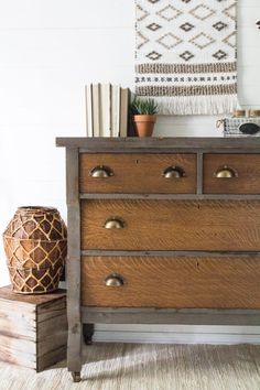 a wooden dresser sitting on top of a white floor next to a potted plant