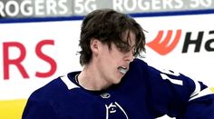 a hockey player with his hands on his hips and mouth open, standing in front of an ice rink