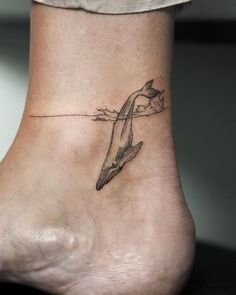 a woman's foot with a dolphin tattoo on it