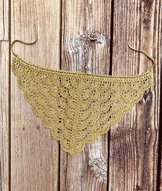 a crocheted triangle is hanging on a wooden fence with an ear hook in the middle