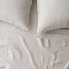 a bed with white sheets and pillows on top of it