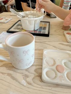 two people sitting at a table with some food in front of them and one holding a spoon