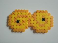 two yellow and orange beads with black eyes on white surface next to eachother