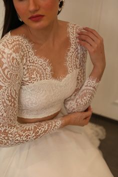 a woman in a white wedding dress is holding her hands on her chest and looking at the camera