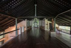 an empty room with wooden floors and white pillars on either side of the room is a statue