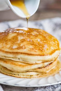 a stack of pancakes with syrup being poured on top