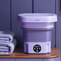 a purple container sitting on top of a wooden counter next to towels and blankets in front of it