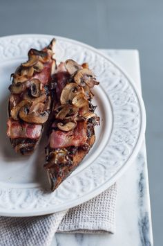 two slices of pizza on a plate with mushrooms and bacon toppings, ready to be eaten