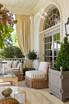 an outdoor living room with wicker furniture and potted plants on the balcony area