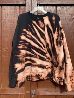 a black and brown tie dye shirt hanging on a wooden door