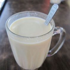 a glass mug filled with milk sitting on top of a wooden table