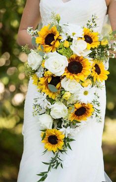 a bride holding a bouquet of sunflowers and white roses on her wedding day