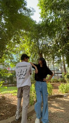 two people walking down a path in the park, one holding his arm around the other's back