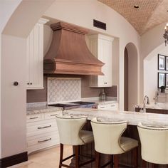 a large kitchen with white cabinets and marble counter tops is pictured in this image, there are four stools at the center of the island