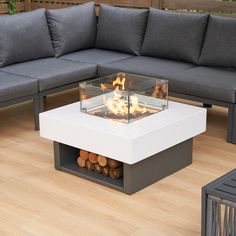 a fire pit sitting on top of a wooden floor next to a couch and coffee table