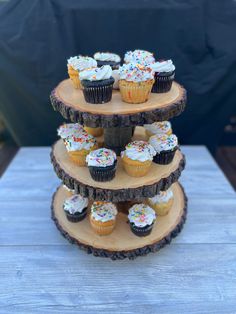 three tiered cupcake display with white frosting and sprinkles on top