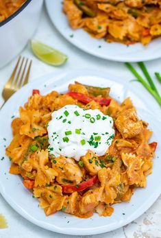 two white plates topped with pasta and veggies next to a pot of sour cream