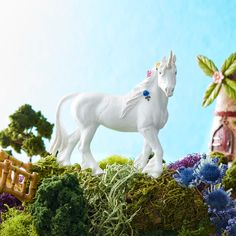 a white horse figurine sitting on top of a lush green field next to a house