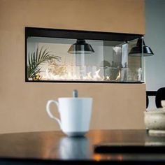 a coffee cup sitting on top of a wooden table next to a window filled with plants