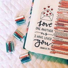 an open bible with love on it next to some mini erases and pencils