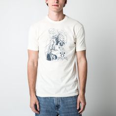 a man standing in front of a white wall wearing a t - shirt with an image of superman on it