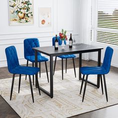 a dining room table with blue chairs and a rug on the floor in front of it