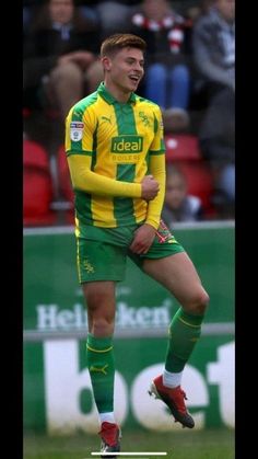 a man in green and yellow uniform kicking a soccer ball