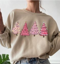 Festive pink trees add a little fun to the holiday season. Four Christmas trees across the front of the sweatshirt.  Sweatshirt sizing fits true to size.  We ship between 7 to 10 days based up on the inventory. Clothing is made to order. Made to order. Pink Long Sleeve Tops For Festive Occasions, Pink Long Sleeve Festive Tops, Holiday Pink Long Sleeve Tops, Pink Long Sleeve Holiday Top, Festive Pink Crew Neck Top, Pink Festive Winter Top, Festive Long Sleeve Fall Sweatshirt, Casual Festive Sweatshirt For Fall, Pink Cotton Holiday Sweatshirt