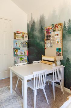 a white table and chairs in front of a forest mural