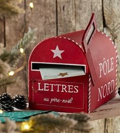 a red mailbox sitting on top of a wooden table next to a christmas tree