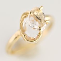 a yellow gold ring with an oval cut diamond in the center, on a white background