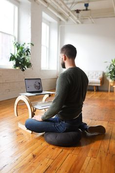 a man sitting on the floor in front of a laptop