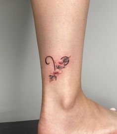 a woman's foot with a small tattoo on the side of her leg and flowers