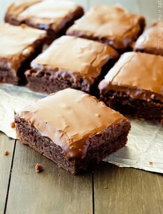 chocolate brownies with frosting sitting on top of a wooden table