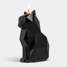 a small black cat candle holder with a lit candle in it's back end