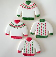 four decorated cookies in the shape of sweaters