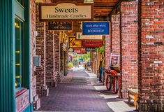 an alley way with brick buildings and signs hanging from the ceiling, along with shops on both sides