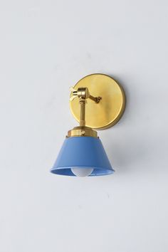 a wall light with a blue shade on the side and a gold plated arm