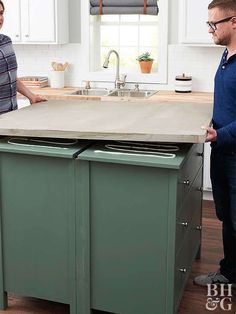 two people standing in a kitchen next to an island with drawers on the top and bottom