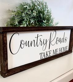 a wooden sign that says country roads take me home on the side of a wall