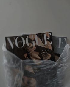 two magazines sitting in plastic bags on top of a white table next to each other