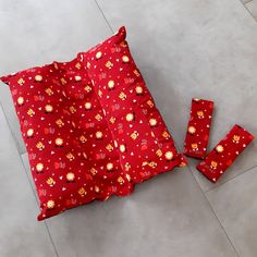 a red cloth with flowers on it laying on the floor next to four pieces of fabric