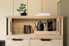 a shelf with two cups, a kettle and a coffee pot on it