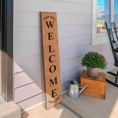 a welcome sign on the front porch of a house with a potted plant next to it