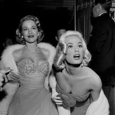 black and white photograph of two women dressed in evening gowns, one with her mouth open