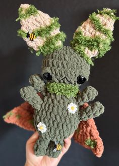 a crocheted stuffed animal with flowers on it's head is being held by someone